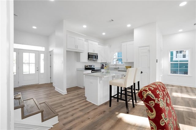 kitchen featuring white cabinets, stainless steel appliances, a kitchen island, and a breakfast bar area