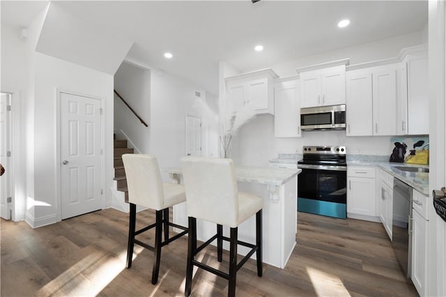 kitchen featuring a center island, dark hardwood / wood-style flooring, white cabinets, and appliances with stainless steel finishes