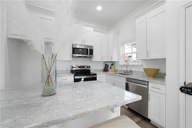 kitchen with light stone counters, sink, white cabinets, and appliances with stainless steel finishes