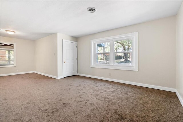 carpeted spare room featuring baseboards and visible vents