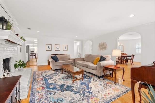 living room with ornamental molding and a brick fireplace