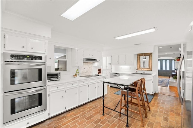 kitchen with white cabinets, appliances with stainless steel finishes, tasteful backsplash, and sink