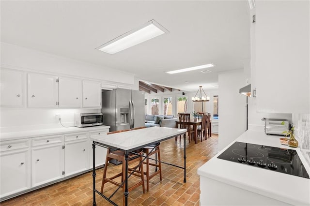 kitchen featuring an inviting chandelier, white cabinets, and appliances with stainless steel finishes