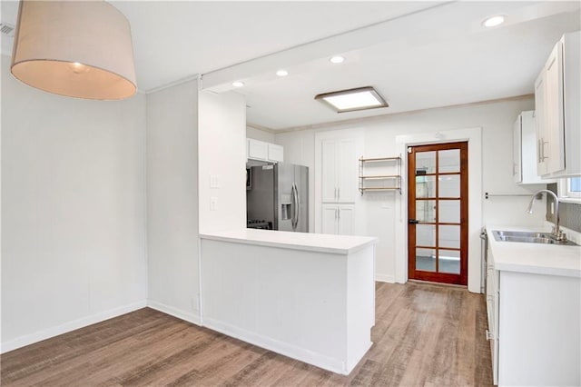 2014 Bakers Ln, Mobile, AL 36605 - kitchen with a sink, stainless steel fridge, white cabinets, light wood finished floors, and light countertops