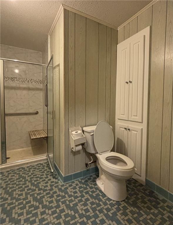 bathroom with wood walls, toilet, a textured ceiling, and a shower with door