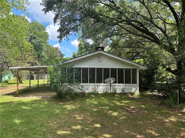 back of property with a lawn and a carport