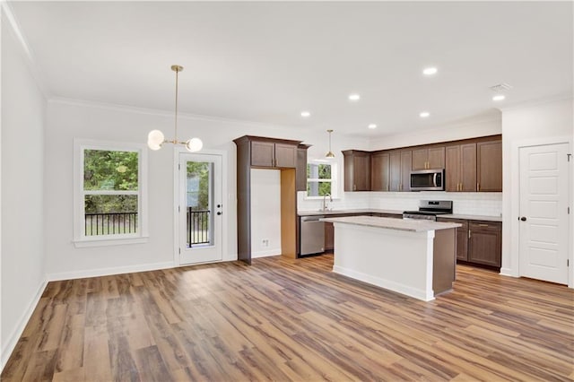 8760 Floyd Crabtree Way, Semmes, AL 36575 - kitchen featuring light wood-type flooring, decorative backsplash, a center island, and stainless steel appliances