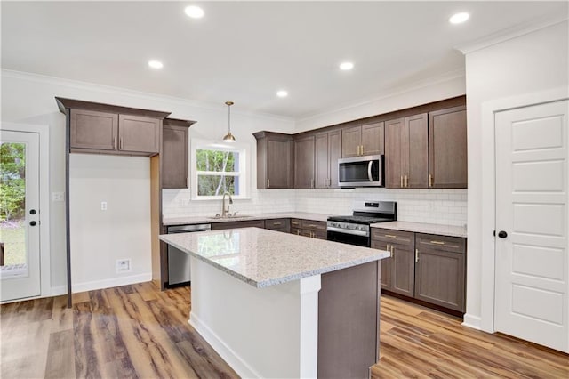 8760 Floyd Crabtree Way, Semmes, AL 36575 - kitchen with dark brown cabinetry, a sink, stainless steel appliances, tasteful backsplash, and a kitchen island