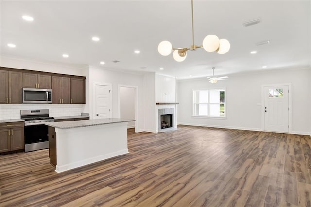 8760 Floyd Crabtree Way, Semmes, AL 36575 - kitchen with backsplash, dark wood-style flooring, crown molding, a center island, and stainless steel appliances