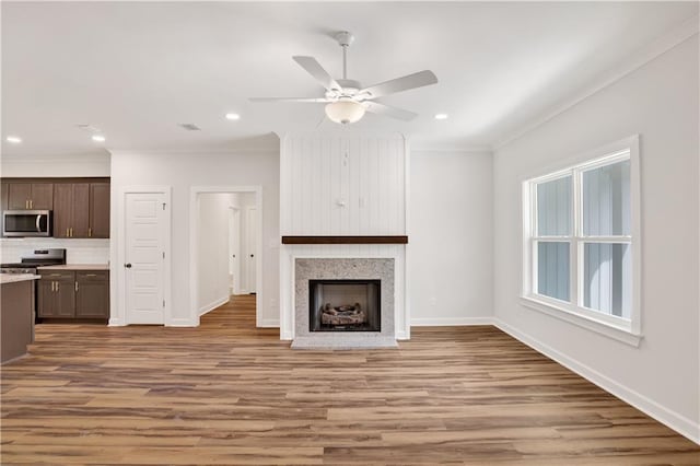 8760 Floyd Crabtree Way, Semmes, AL 36575 - unfurnished living room with crown molding, a fireplace with flush hearth, baseboards, a ceiling fan, and light wood-style flooring