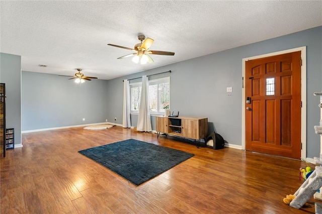 entrance foyer with ceiling fan, baseboards, a textured ceiling, and wood finished floors