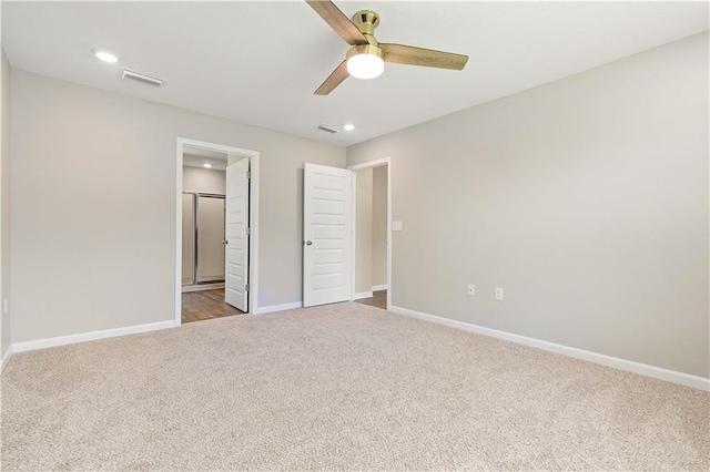 unfurnished bedroom featuring ceiling fan, light colored carpet, and ensuite bath