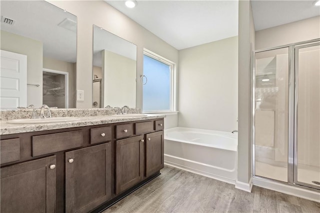 bathroom featuring vanity, hardwood / wood-style floors, and plus walk in shower