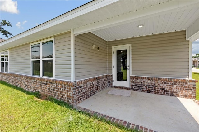 property entrance featuring a lawn and a patio area