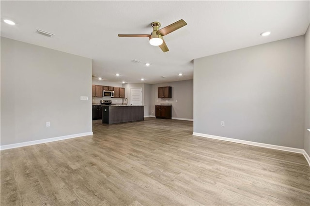 unfurnished living room with hardwood / wood-style floors, ceiling fan, and sink