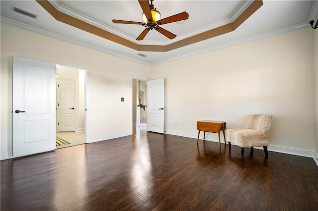 sitting room with dark hardwood / wood-style floors, ceiling fan, ornamental molding, and a tray ceiling