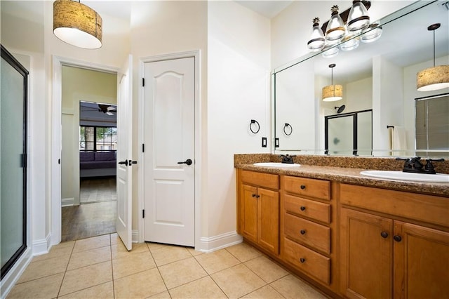 bathroom with a shower with door, vanity, and tile patterned flooring