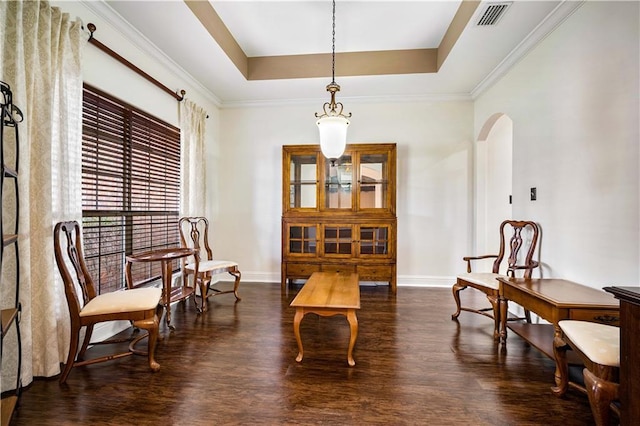 living area featuring dark hardwood / wood-style floors, a raised ceiling, and ornamental molding