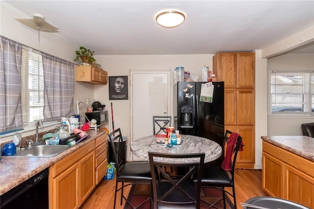 kitchen with light countertops, a sink, light wood-style floors, and black appliances