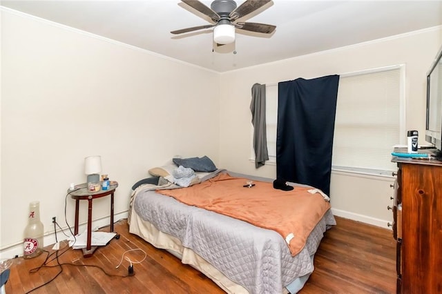 bedroom featuring baseboards, crown molding, wood finished floors, and ceiling fan