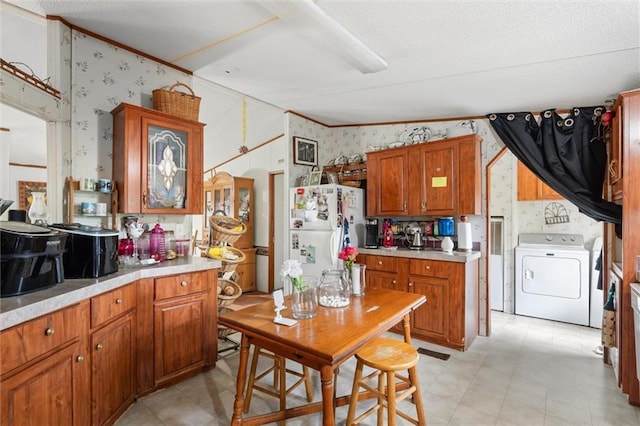 kitchen featuring washer / clothes dryer, vaulted ceiling, and white fridge