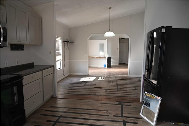 kitchen with decorative light fixtures, dark wood-type flooring, black appliances, and vaulted ceiling