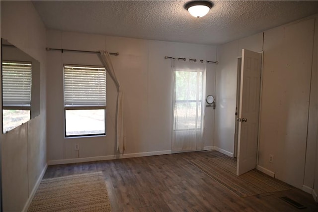 spare room with dark hardwood / wood-style floors and a textured ceiling