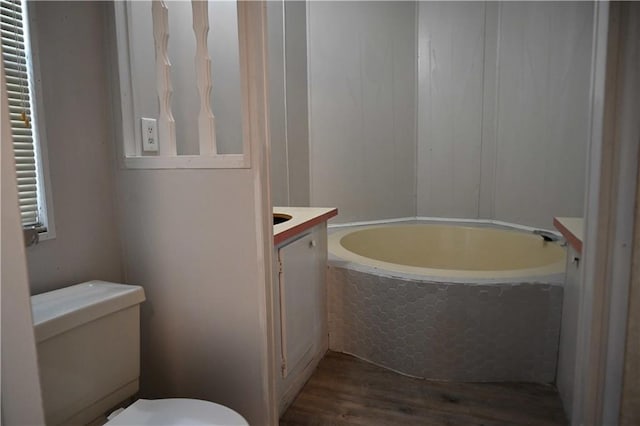 bathroom with hardwood / wood-style flooring, vanity, toilet, and a bath