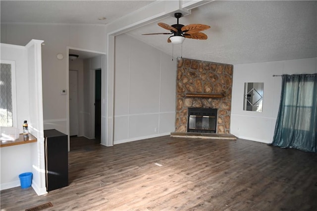 unfurnished living room with ceiling fan, dark wood-type flooring, vaulted ceiling with beams, a stone fireplace, and a textured ceiling