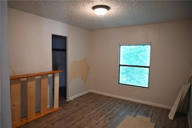 empty room featuring a textured ceiling and dark hardwood / wood-style floors