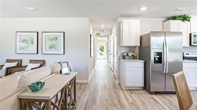 kitchen with white cabinets, stainless steel appliances, and light hardwood / wood-style floors