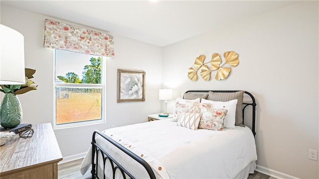 bedroom with multiple windows and hardwood / wood-style flooring