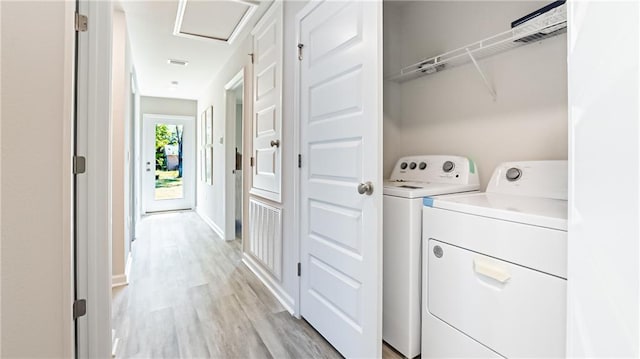 clothes washing area featuring separate washer and dryer and light hardwood / wood-style flooring