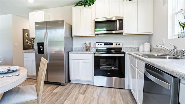 kitchen with sink, white cabinetry, stainless steel appliances, and light wood-type flooring