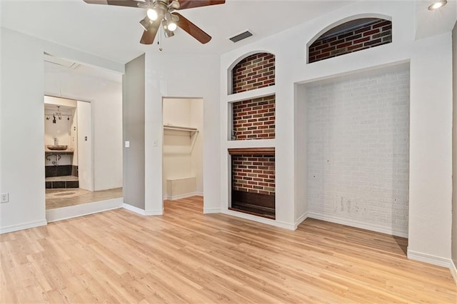 interior space featuring brick wall, light hardwood / wood-style flooring, and ceiling fan