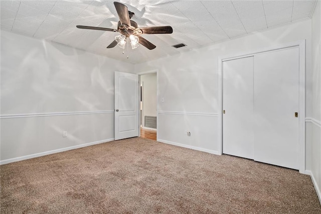 unfurnished bedroom with a closet, carpet, and ceiling fan