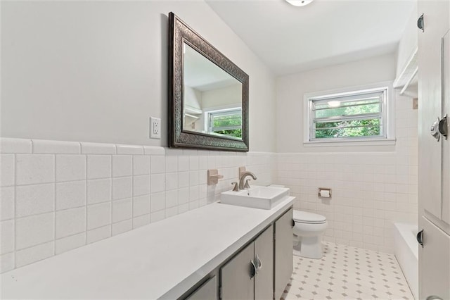 bathroom with a tub, toilet, tile patterned flooring, vanity, and tile walls