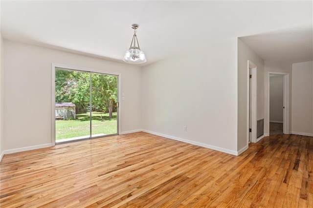 empty room with a chandelier and light hardwood / wood-style floors