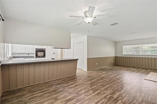 kitchen featuring oven, kitchen peninsula, white cabinets, ceiling fan, and dark hardwood / wood-style floors