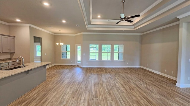 unfurnished living room with ornamental molding, light wood-type flooring, ceiling fan with notable chandelier, and sink