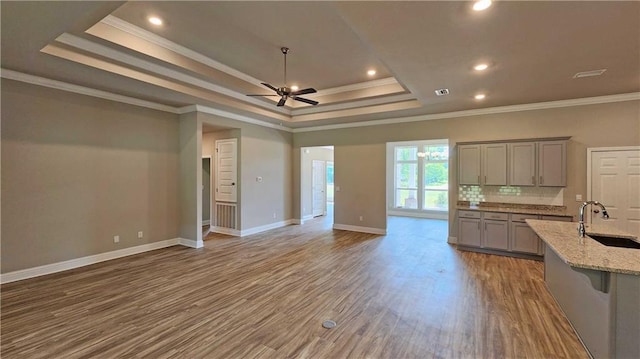 kitchen with light stone counters, hardwood / wood-style floors, gray cabinetry, ceiling fan, and crown molding