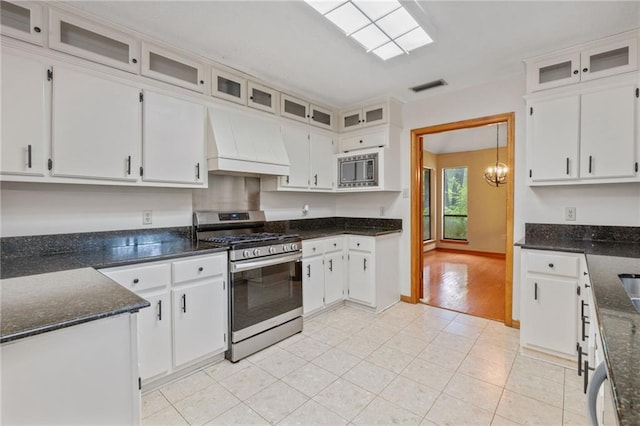 562 Vaughn Dr N, Satsuma, AL 36572 - kitchen featuring stainless steel appliances, custom exhaust hood, white cabinets, and dark stone counters