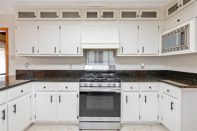 562 Vaughn Dr N, Satsuma, AL 36572 - kitchen featuring stainless steel appliances, custom range hood, dark stone counters, glass insert cabinets, and white cabinets
