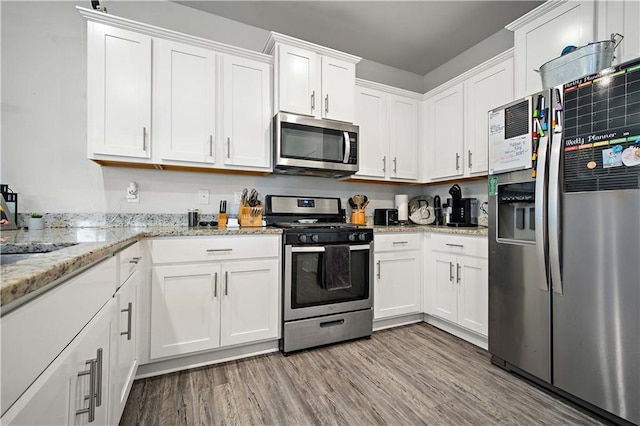 24341 Alydar Loop, Daphne, AL 36526 - kitchen featuring appliances with stainless steel finishes, white cabinets, light wood-style floors, and light stone counters