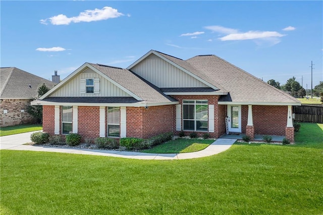 view of front of property with a shingled roof, a front yard, fence, and brick siding