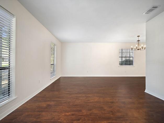 unfurnished room with a notable chandelier and dark hardwood / wood-style flooring