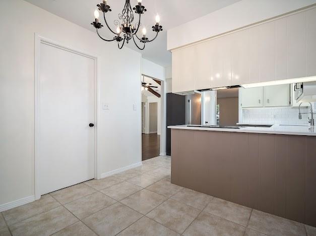 kitchen with kitchen peninsula, decorative backsplash, sink, and light tile patterned floors