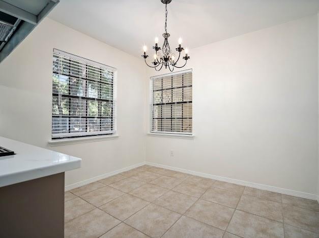 unfurnished dining area featuring an inviting chandelier and light tile patterned floors