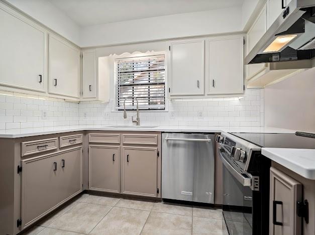 kitchen with light tile patterned flooring, sink, decorative backsplash, white cabinets, and appliances with stainless steel finishes