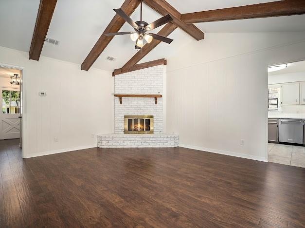 unfurnished living room featuring a brick fireplace, hardwood / wood-style floors, vaulted ceiling with beams, and ceiling fan